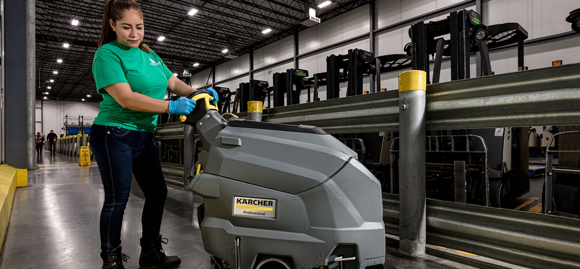 Photo of a Level Seven worker cleaning a factory floor with a commercial floor scrubbing machine