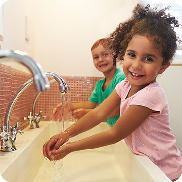 Photo of two children washing their hands in a school bathroom