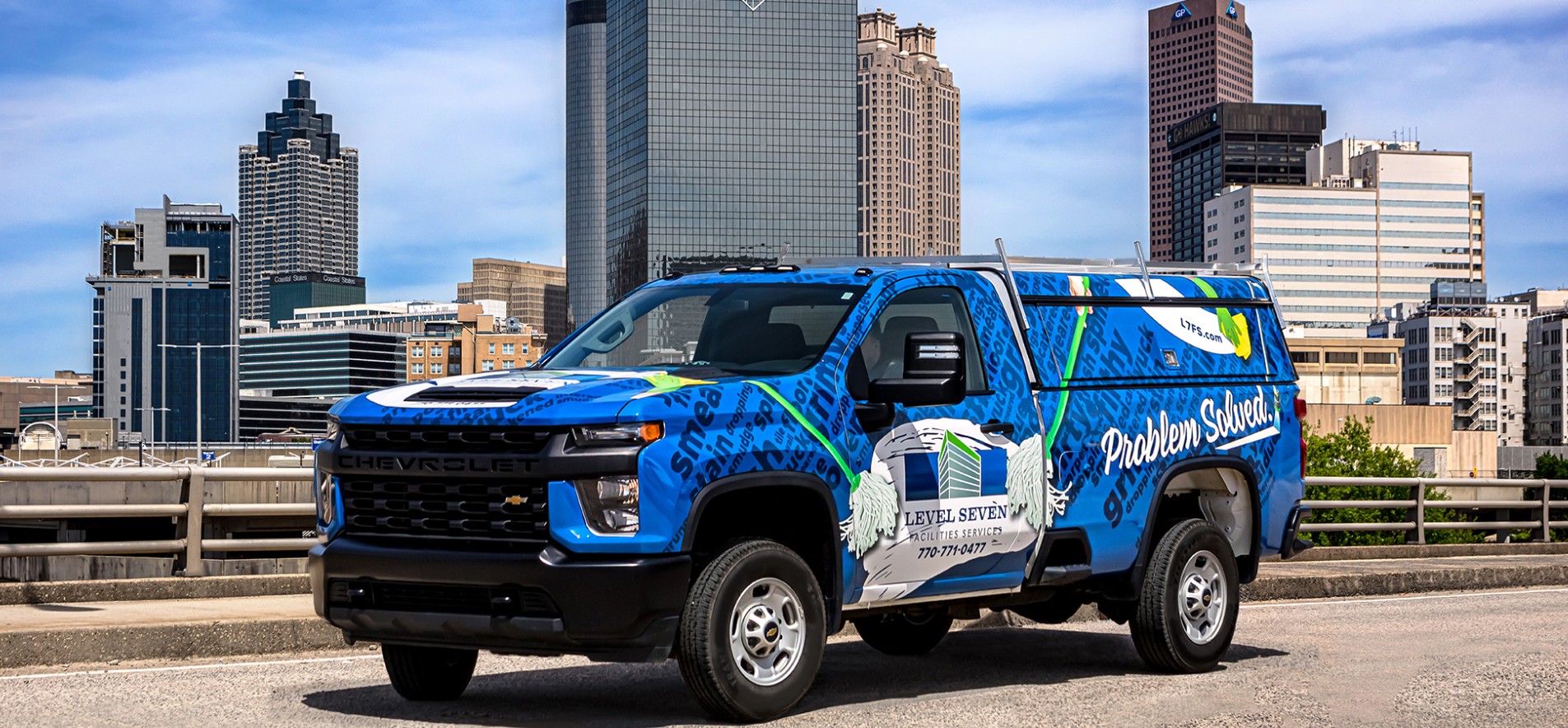 Photo of a colorful Level Seven service truck, with the Atlanta skyline in the background