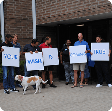 Photo of six employees of Level Seven holding signs that read "Your wish is coming true"